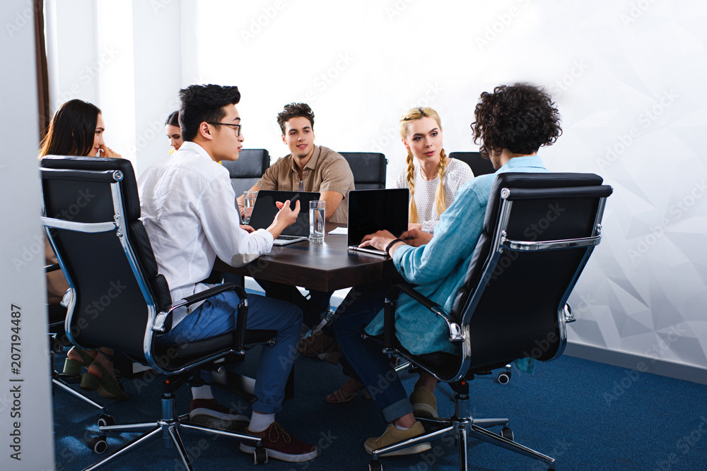 multiethnic business people having discussion at table with laptops in modern office multiethnic business people having discussion at table with laptops in modern office