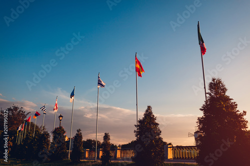 A row of flying flags of nations on sunset sky background. Flags of different countries in summer park photo