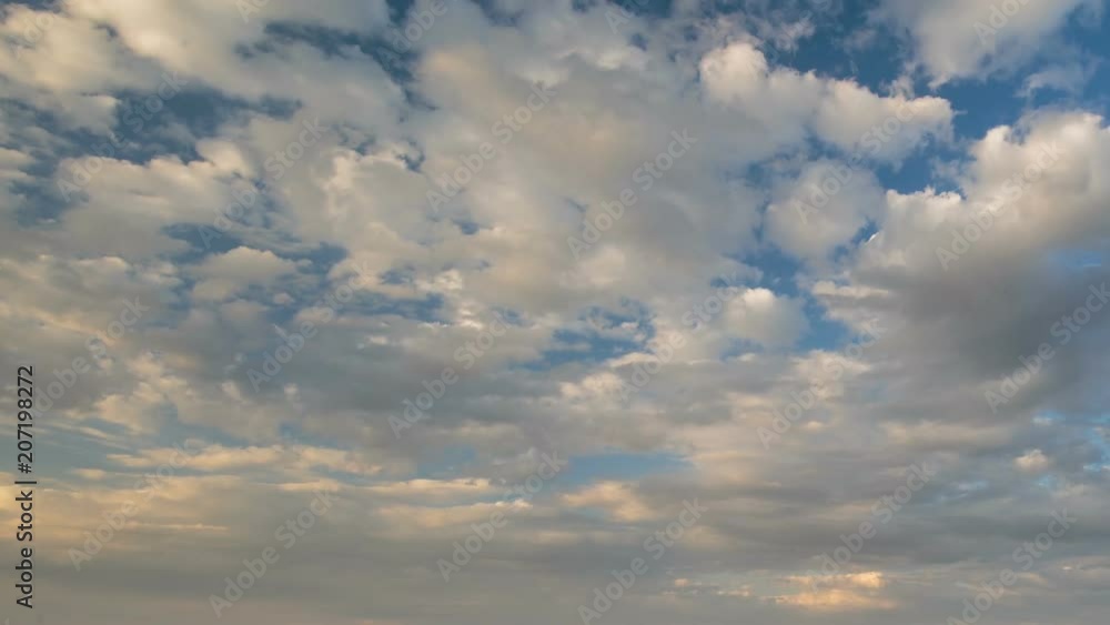 Russia, time lapse. Formation and rapid movement of white clouds of different shapes in the blue sky in late spring at sunset.