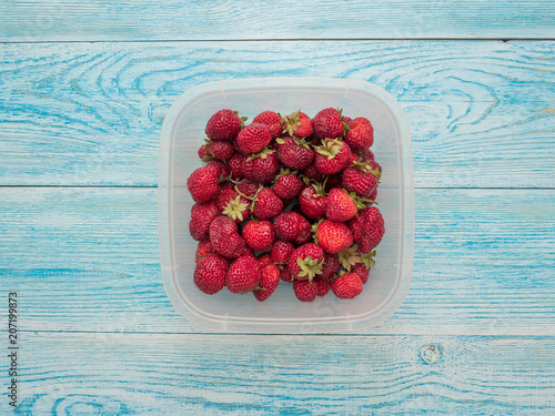 Strawberries in a container on a wooden table