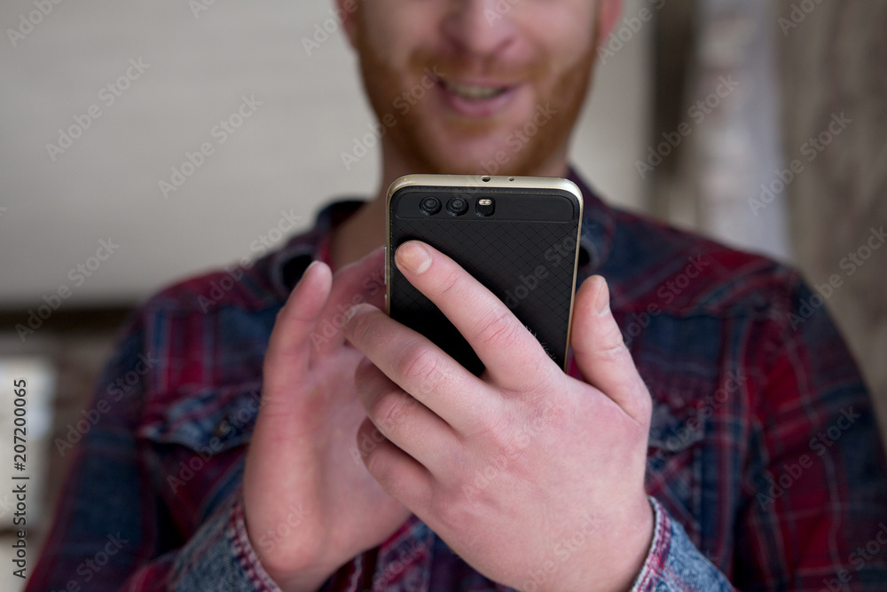 Man holding phone in his hands scrolling through news. Close up of young male with beard holding smart phone with dual camera. Man holding phone in his hands scrolling through news. Close up of young male with beard holding smart phone with dual camera.