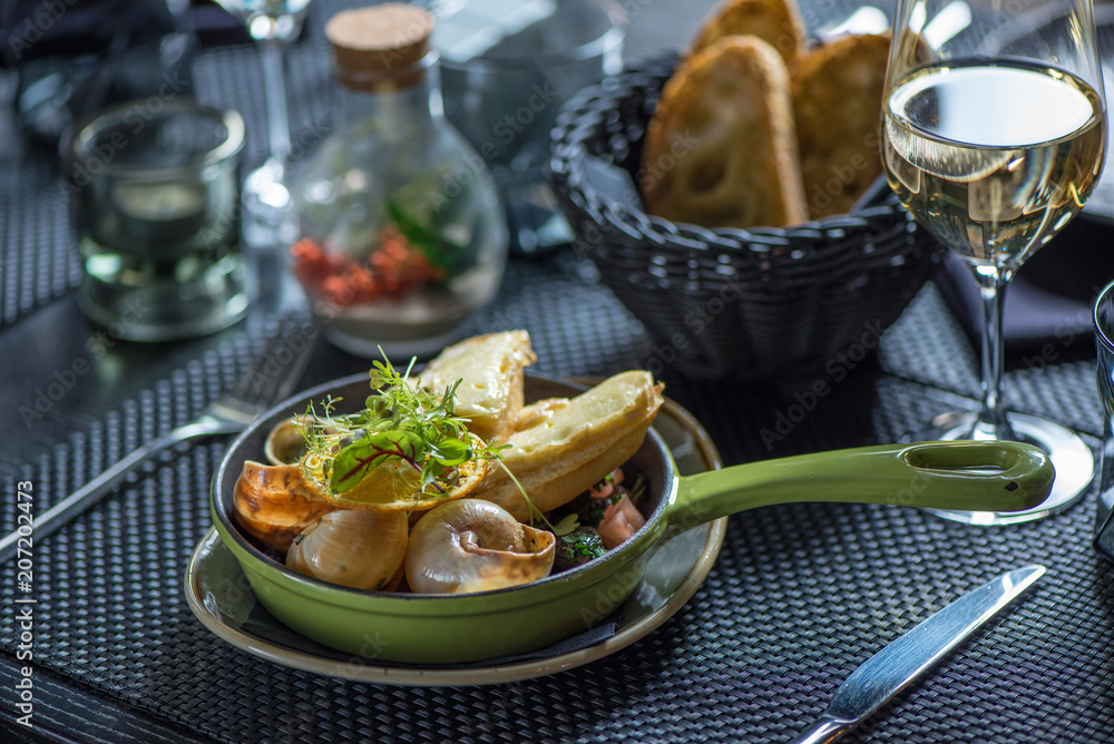 Frying pan with escargot snails with garlic butter, rustic wooden surface, selective focus Frying pan with escargot snails with garlic butter, rustic wooden surface, selective focus