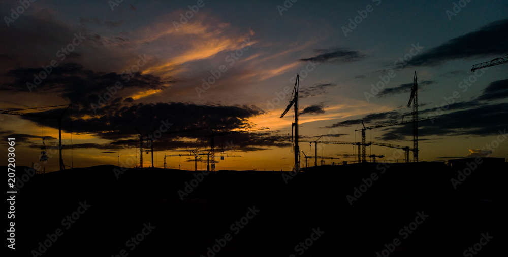 silhouette of construction tower crane group with sunset sky background