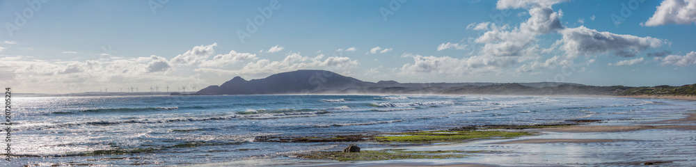 Green Point Beach in Tasmania, Australia, with a wind farm visible in the distance Green Point Beach in Tasmania, Australia, with a wind farm visible in the distance