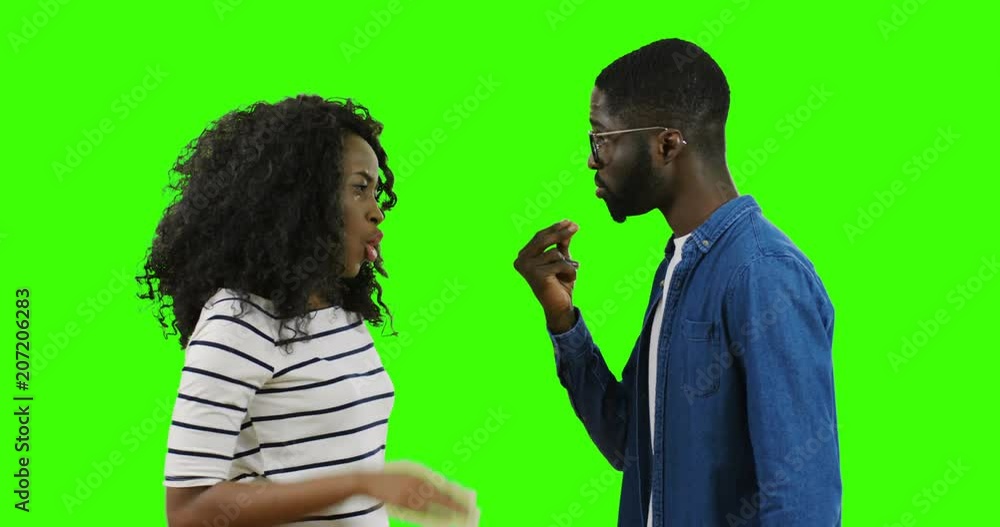 African American young boyfriend and girlfriend quarreling and fighting face to face while being on the green screen backgroud. Chroma key. African American young boyfriend and girlfriend quarreling and fighting face to face while being on the green screen backgroud. Chroma key.