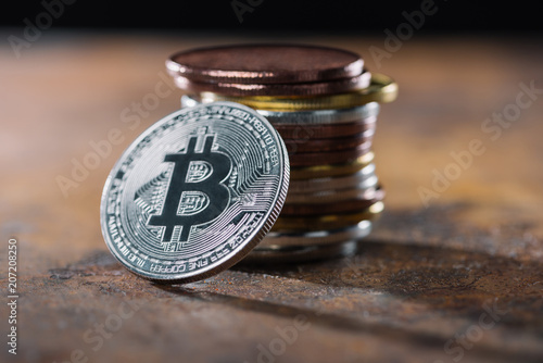 selective focus of silver bitcoin and pile of bitcoins behind photo