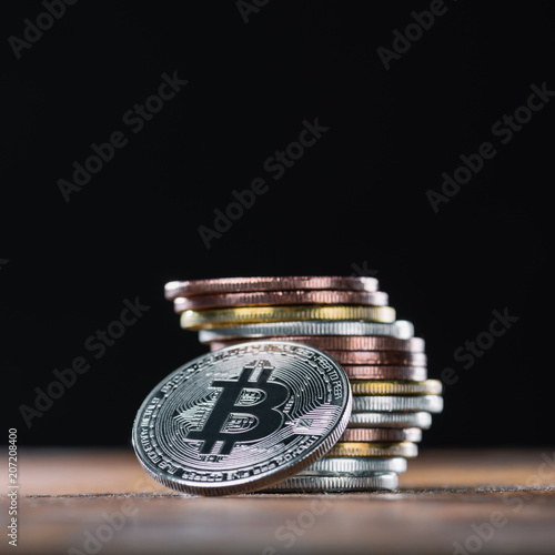 Close up view of bitcoin leaning on stack of various bitcoins on black background photo