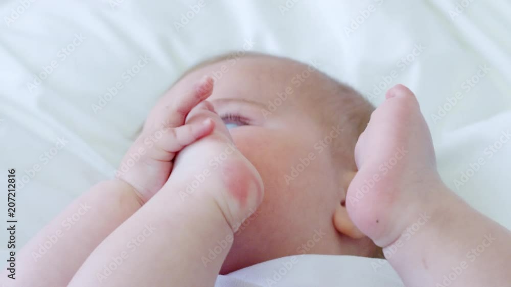 Baby Boy Lying On Bed And Holding Feet