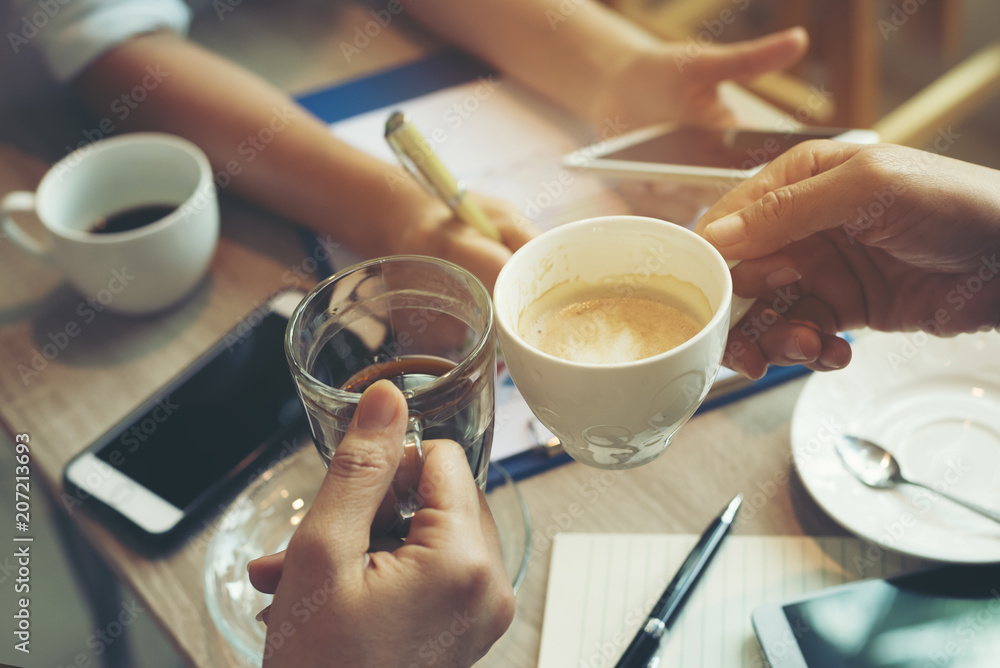 In the meeting time the company's operation, Business team consultations and meeting,summary of sales on table near cup of hot coffee and hand phone.