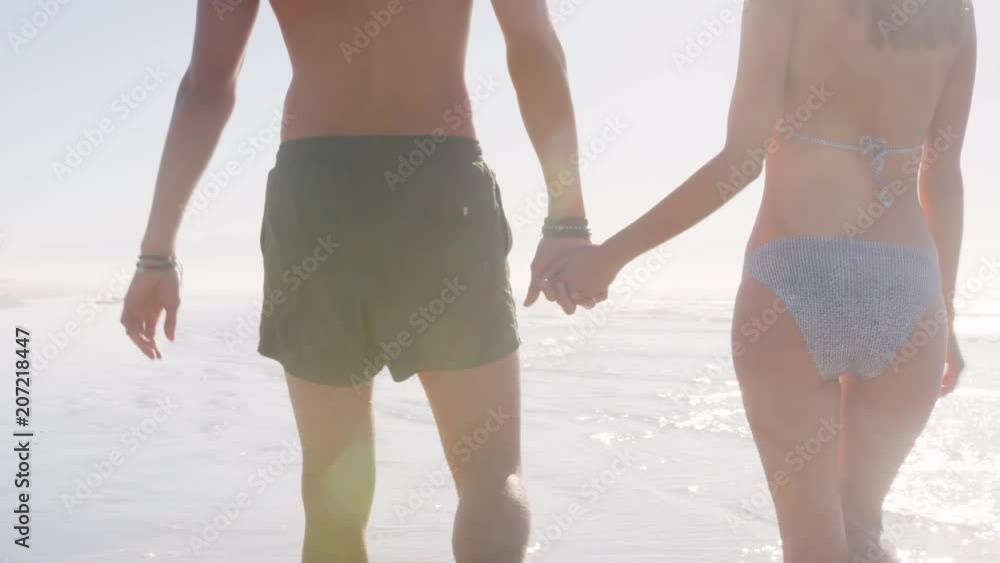 Close Up Of Couples Walking Along Shoreline On Beach Vacation Close Up Of Couples Walking Along Shoreline On Beach Vacation