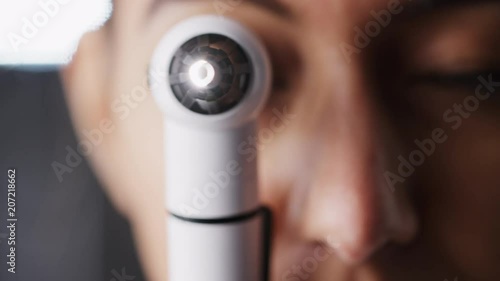 Woman using otoscope for an examination, close up