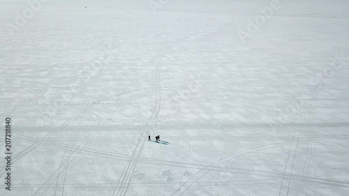 Three travelers walk along the Arctic ice of the frozen sea, shooting from the quadrocopter.