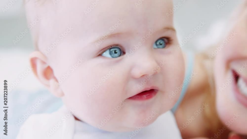 Close Up Of Mother Playing On Bed At Home With Baby Son Close Up Of Mother Playing On Bed At Home With Baby Son