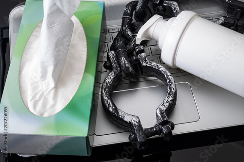 Porn and masturbation concept with close up on a bottle of moisturizing  lotion or lube, a chain representing addiction and a box of paper tissues  next to a computer Stock Photo