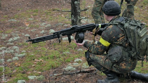 Soldiers in camouflage with combat weapons are being fired in the shelter of the forest, the military concept photo