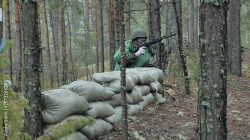 Soldiers in camouflage with combat weapons are being fired in the shelter of the forest, the military concept photo