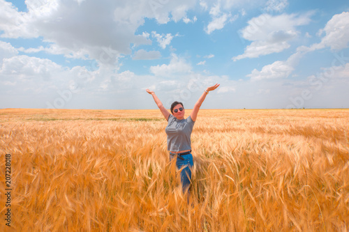 Woman in a golden wheat field on the background cloudy sky