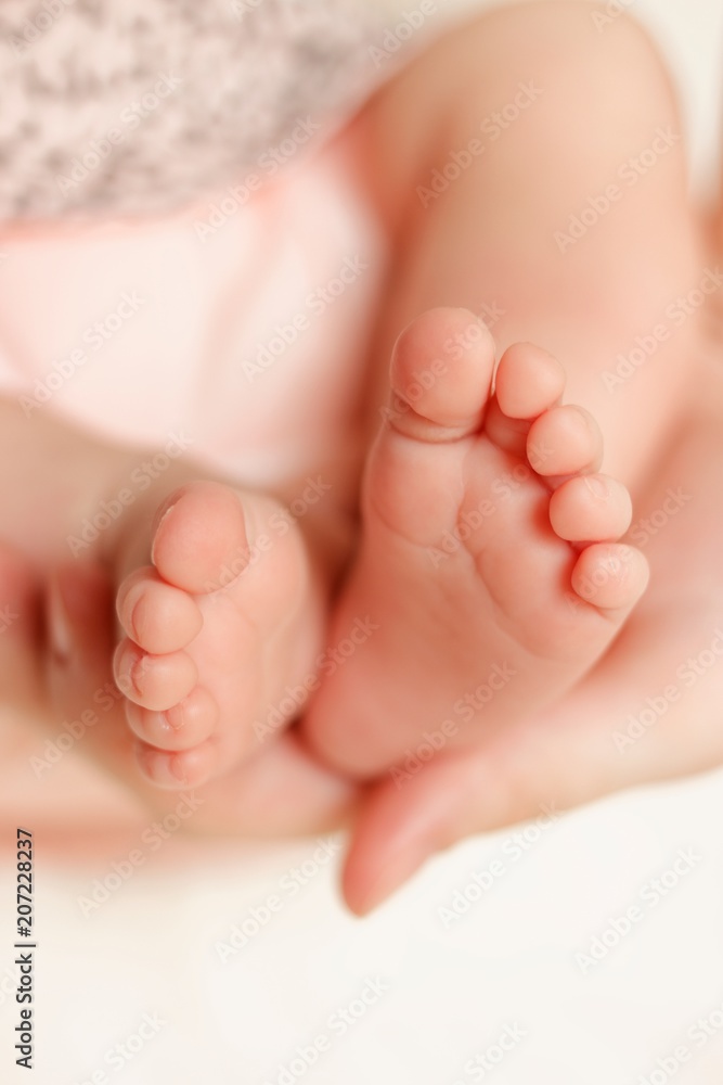 mother hold feets of newborn baby