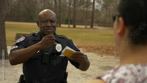 An African American police officer talks with a female citizen for crime prevention.