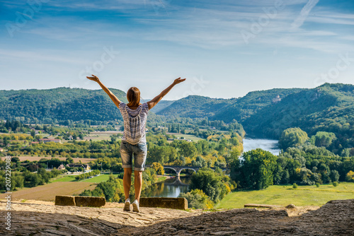 Summer vacation. Girl with a backpack raised her hands up. Beautiful rural landscape. tourist girl enjoys a beautiful view of the valley. 