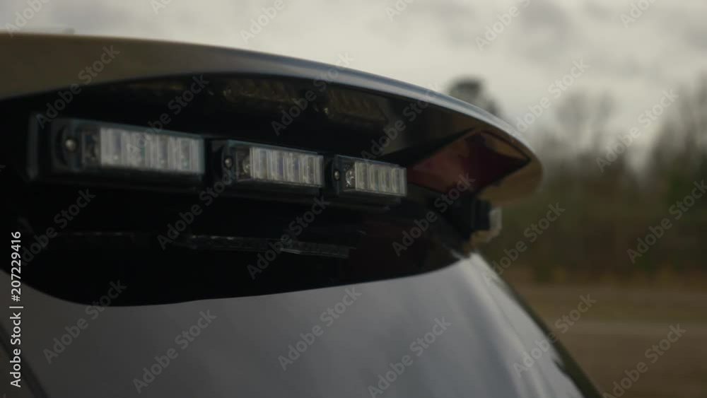 A police car sits in a neighborhood with its blue lights on.