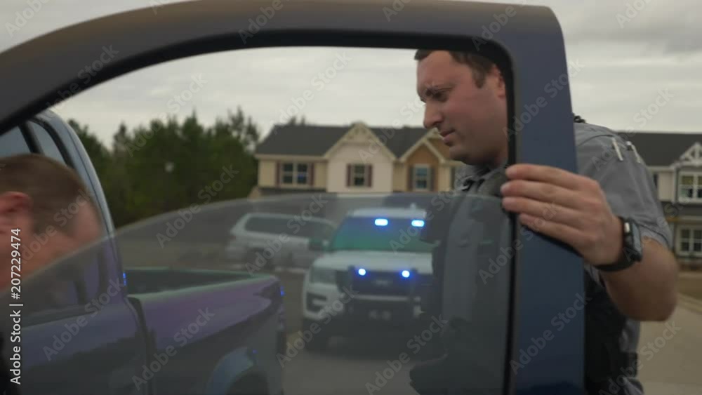 A police officer gets a possible criminal out of his truck during a traffic stop for law enforcement. A police officer gets a possible criminal out of his truck during a traffic stop for law enforcement.