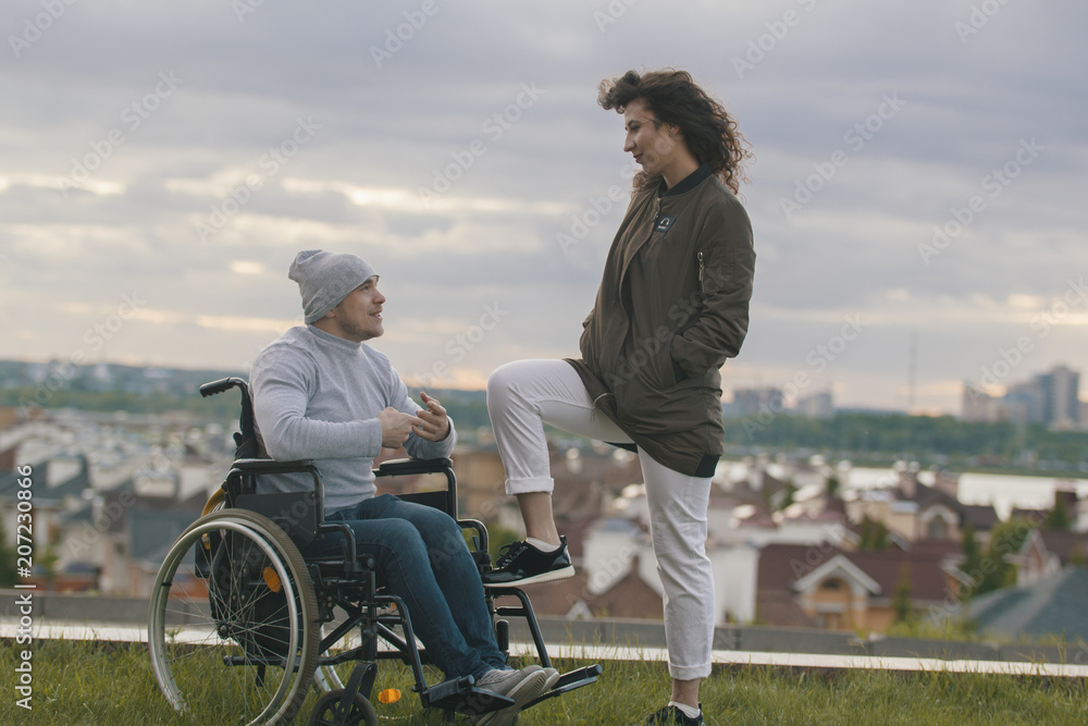 Beautiful woman with young disabled man on the hill overlooking the city Beautiful woman with young disabled man on the hill overlooking the city