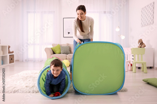 Nanny and little boys playing with toy tunnel at home photo