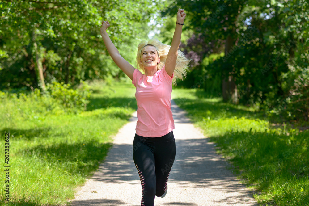 Joyful woman running along a woodland track Joyful woman running along a woodland track