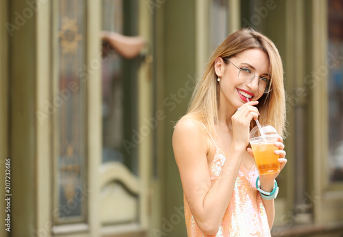 Young woman with cup of tasty lemonade outdoors