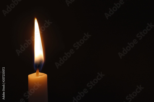 Wax candle burning on black background, closeup