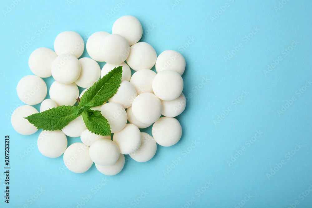 Tasty mint candies and leaves on color background, top view