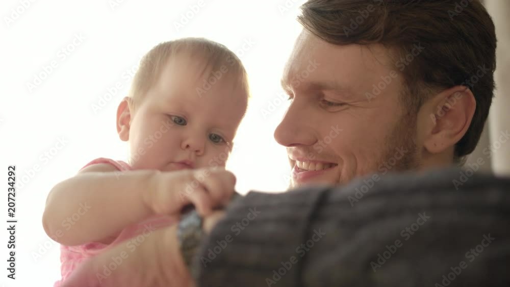 Bearded dad kissing baby. Close up of happy father with child on hands. Baby touching wrist watch on father hand. Father time concept. Dad come back home after work. Daddy kissing child Bearded dad kissing baby. Close up of happy father with child on hands. Baby touching wrist watch on father hand. Father time concept. Dad come back home after work. Daddy kissing child
