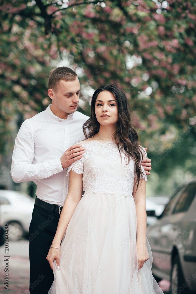 Happy young couple in love enjoys spring day, loving man holding on hands his woman carefree walking at park Happy young couple in love enjoys spring day, loving man holding on hands his woman carefree walking at park