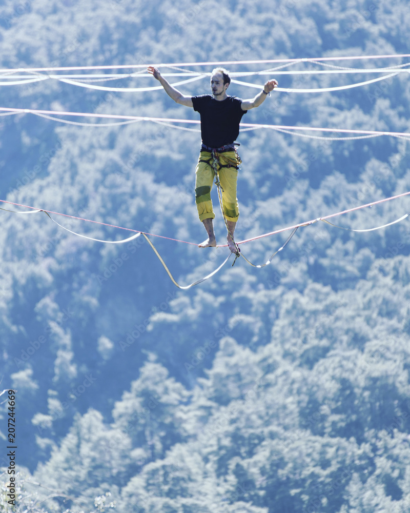 Highliner on a rope. Highline on a background of mountains. Extreme sport on the nature. Balancing on the sling. Equilibrium at altitude. Highliner on a rope. Highline on a background of mountains. Extreme sport on the nature. Balancing on the sling. Equilibrium at altitude.