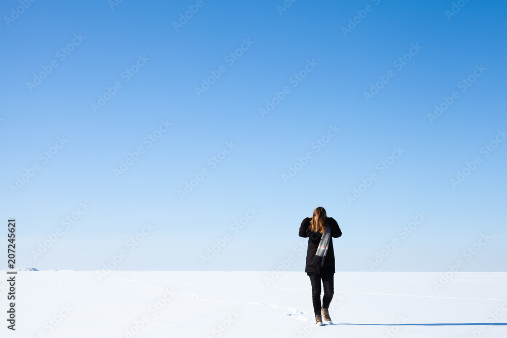Teenage girl walks along endless snowfield Teenage girl walks along endless snowfield