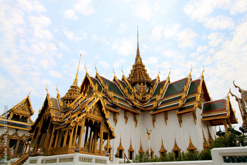 Exterior view of Temple of the Emerald Buddha, buidling of Wat Phra Kaew, Grand - Royal Palace, Bangkok (Krung Thep), Thailand, Asia. Colorful Asian rooftops, golden tower, ornaments and cloudy sky. Exterior view of Temple of the Emerald Buddha, buidling of Wat Phra Kaew, Grand - Royal Palace, Bangkok (Krung Thep), Thailand, Asia. Colorful Asian rooftops, golden tower, ornaments and cloudy sky.
