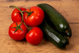 Fresh zucchinis and tomatos on a wooden background