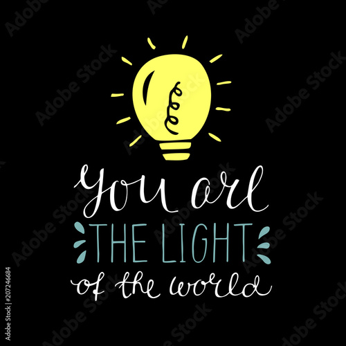 Hand lettering with bible verse You are the light of the world, made with glowing light bulb on black background