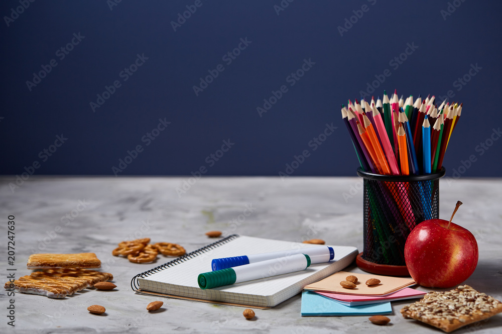 Back to School concept, school supplies, biscuits, packed lunch and lunchbox over white chalkboard, selective focus.