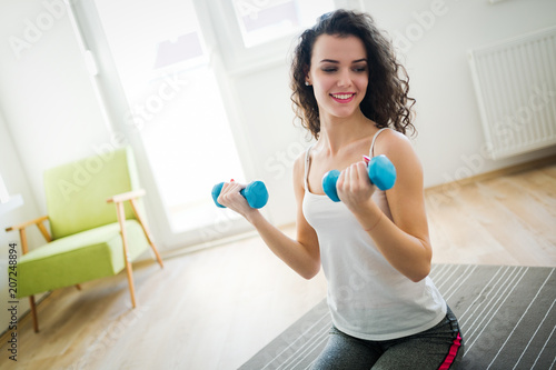 Young attractive sportswoman doing exercises at home
