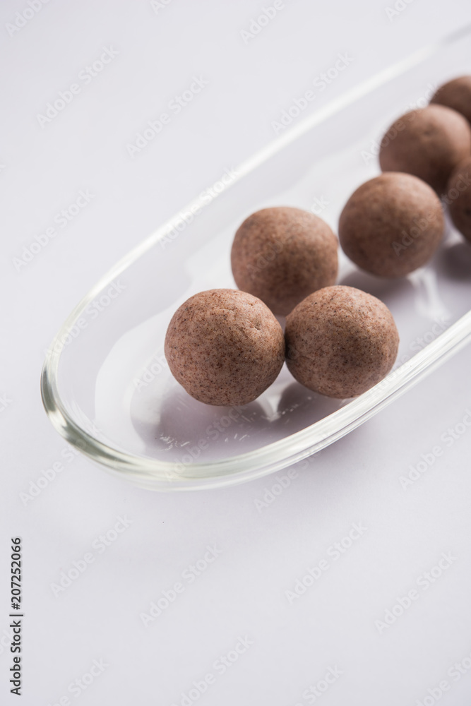 Nachni laddu or Ragi laddoo or balls made using finger millet, sugar and ghee. It's a healthy food from India. Served in a bowl or plate over moody background. Selective focus Nachni laddu or Ragi laddoo or balls made using finger millet, sugar and ghee. It's a healthy food from India. Served in a bowl or plate over moody background. Selective focus