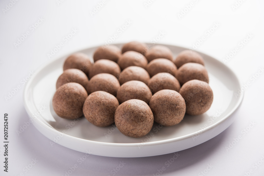 Nachni laddu or Ragi laddoo or balls made using finger millet, sugar and ghee. It's a healthy food from India. Served in a bowl or plate over moody background. Selective focus Nachni laddu or Ragi laddoo or balls made using finger millet, sugar and ghee. It's a healthy food from India. Served in a bowl or plate over moody background. Selective focus