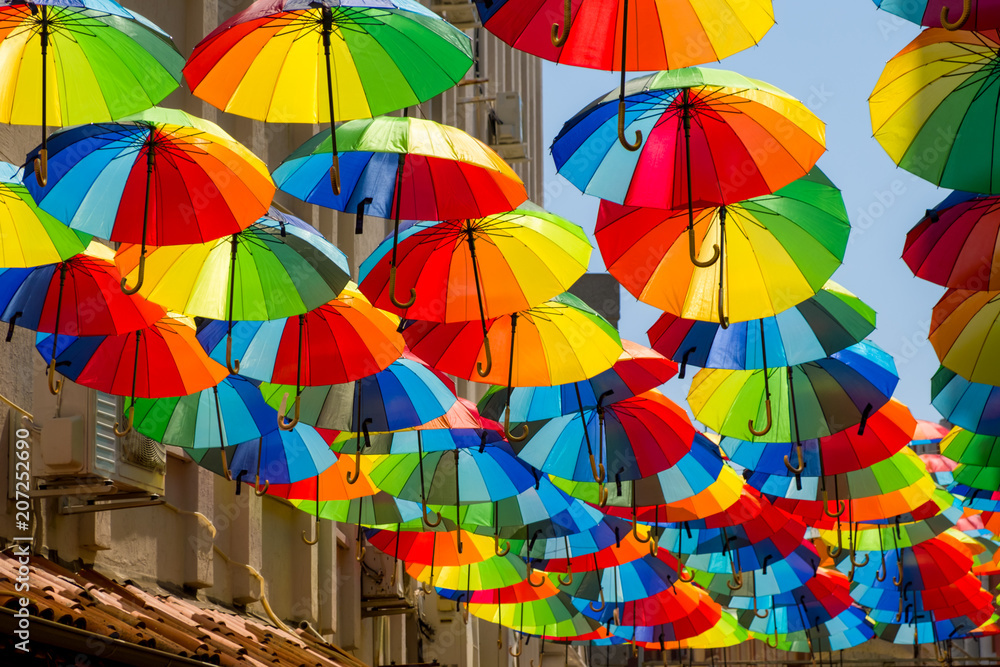 Multicolored, rainbow, umbrellas hung over the street. - obrazy, fototapety, plakaty 