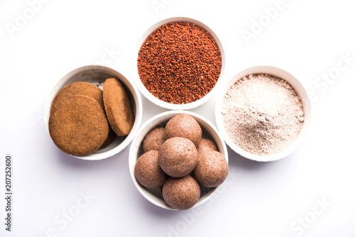 Nachni / Ragi laddu and biscuits or cookies made using  finger millet, sugar and ghee. It's a healthy food from India. Served in a bowl or plate with raw whole and powder. Selective focus photo