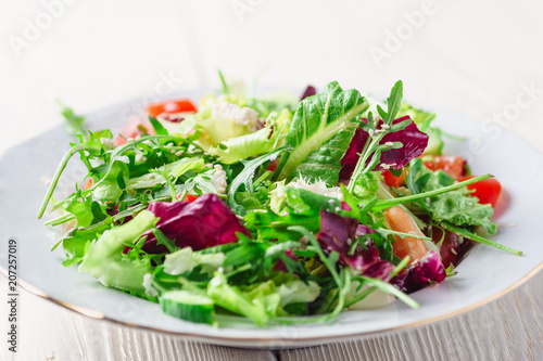 Fresh organic super food salad on white plate with fork on side