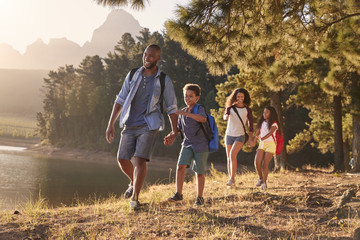 Children Walk By Lake With Parents On Family Hiking Adventure