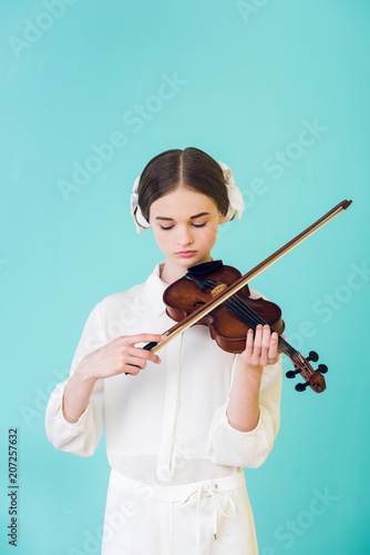 Fototapeta attractive teen girl playing violin, isolated on turquoise