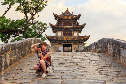 Tourist girl taking pictures on ancient Chinese bridge