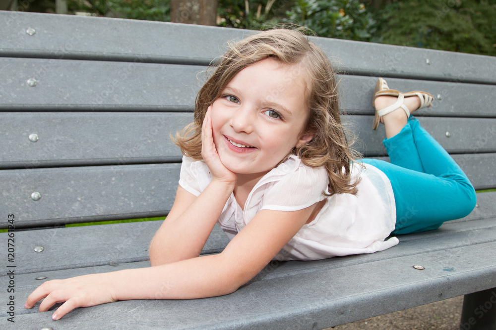 Happy little child girl having fun at bench park posing Happy little child girl having fun at bench park posing